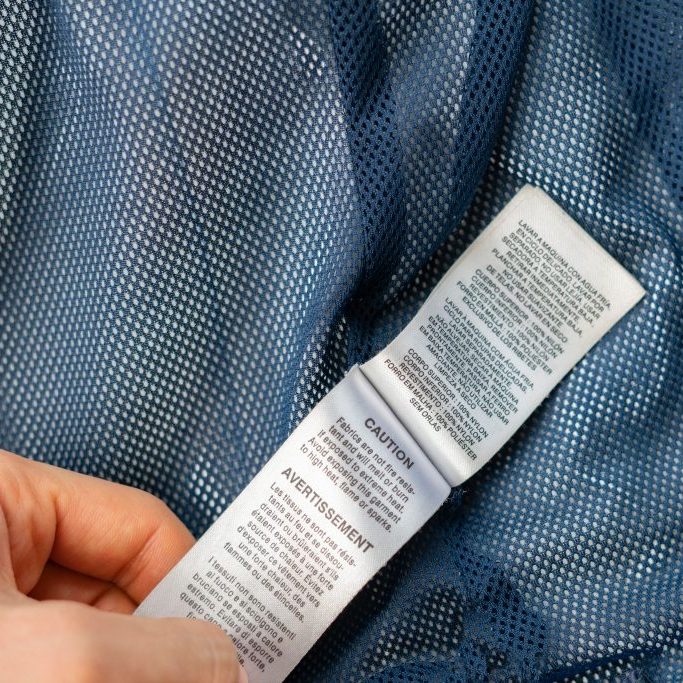 close up woman hand read clothes care label before washing